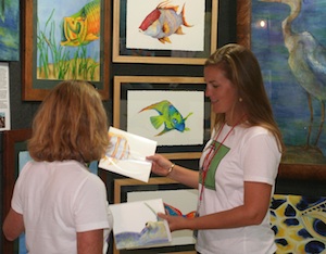 Lowe (right) shares her giclee prints with an art show patron at the Pigeon Key Art Festival, during February in Marathon. 